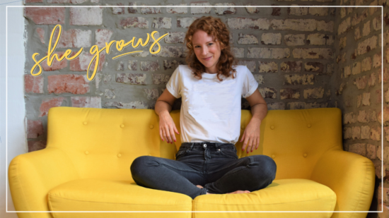 Fröhliche rothaarige Frau sitzt auf einem gelben Sofa vor einer Backsteinwand, Schriftzug she grows, Neuigkeiten rund um den Podcast, kurzes Update